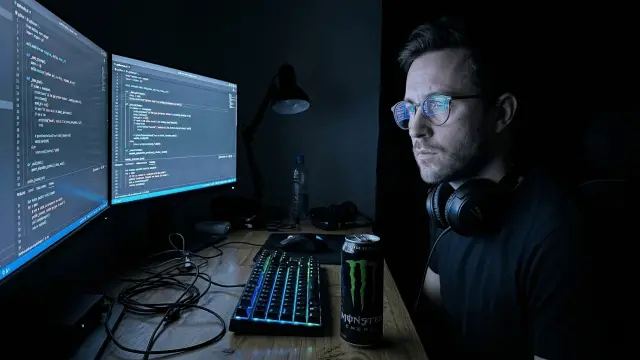 Developer working late at computer monitors for SaaS and software companies